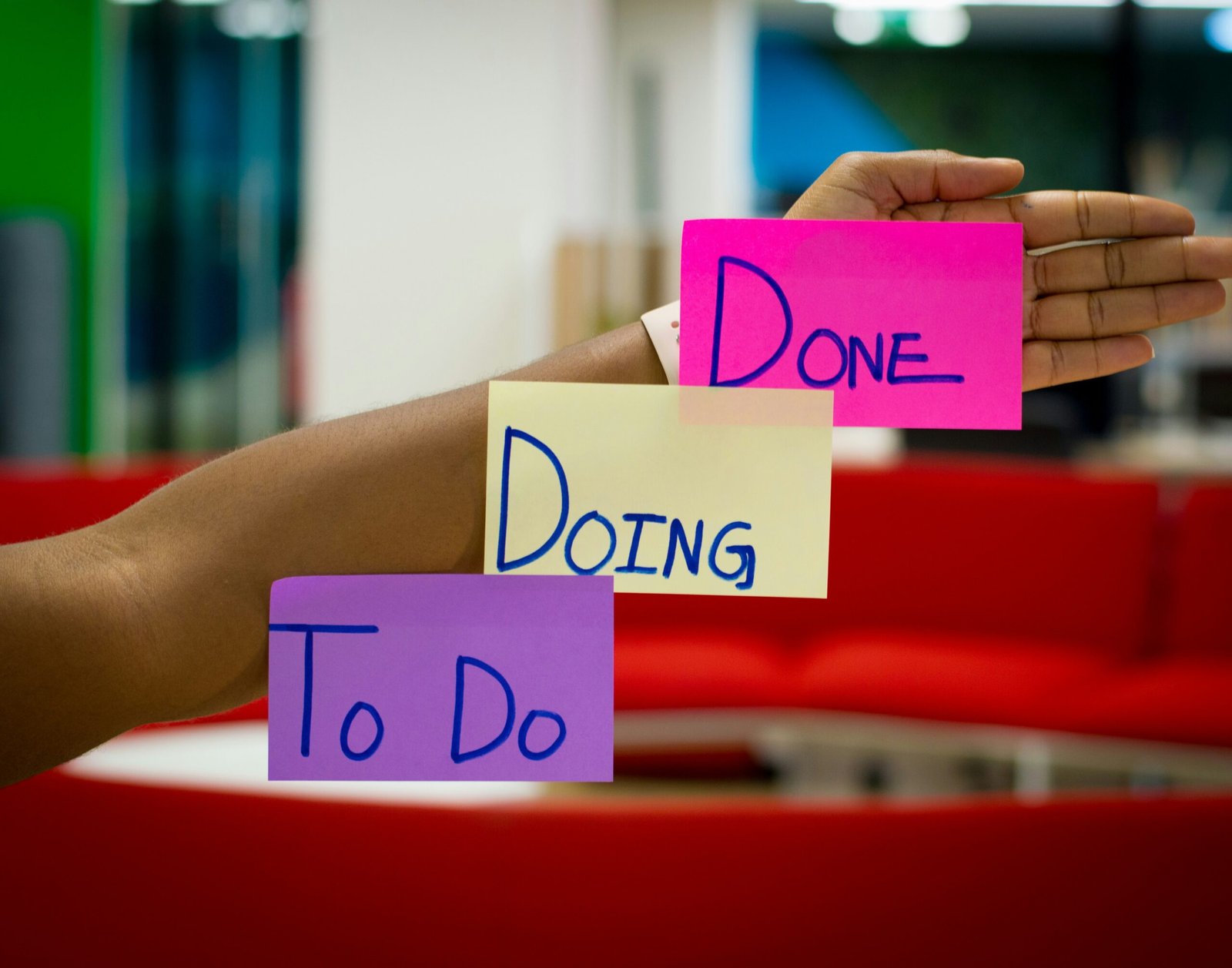 Arm extended with sticky notes labeled 'To-do,' 'Doing,' and 'Done,' representing task management and workflow organization